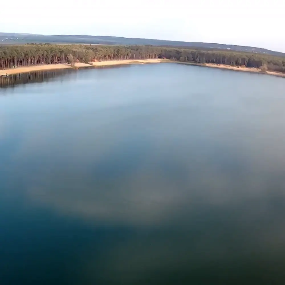 Podzim nad jezerem: klidná hladina zrcadlí mraky, záběr z dronu